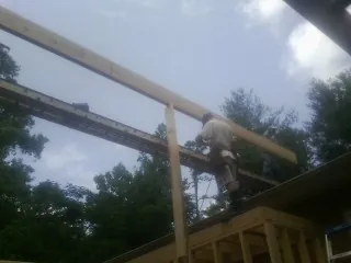 Carpenter setting a ridge beam over a new addition frame — Ice Dam Removal by Roofing Brothers in Meadow Grove