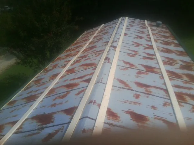 Rusted metal roof panels with new wood purlins before replacement — Storm Damage Roof Repair in Meadow Grove by Roofing Brothers