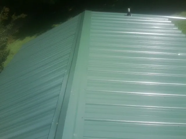 New green metal panels meeting at the ridge of a roof in Meadow Grove