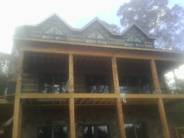 Dormers and porch framing on a large log home under construction — Roof Coating work by our crew in Meadow Grove