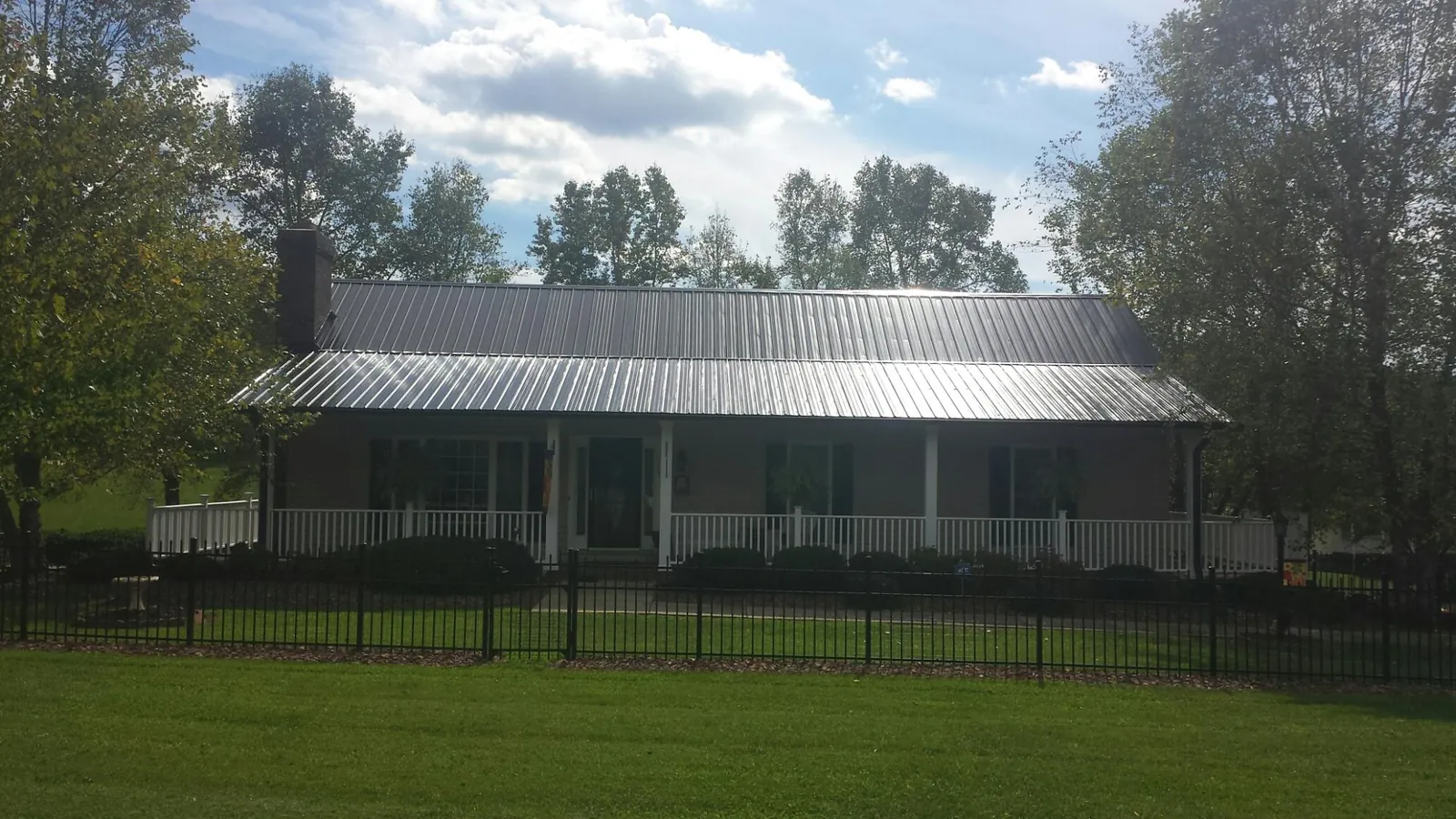 Gray metal roof on a brick ranch with a full width front porch — Gutter Guard Installation work by our crew in Meadow Grove