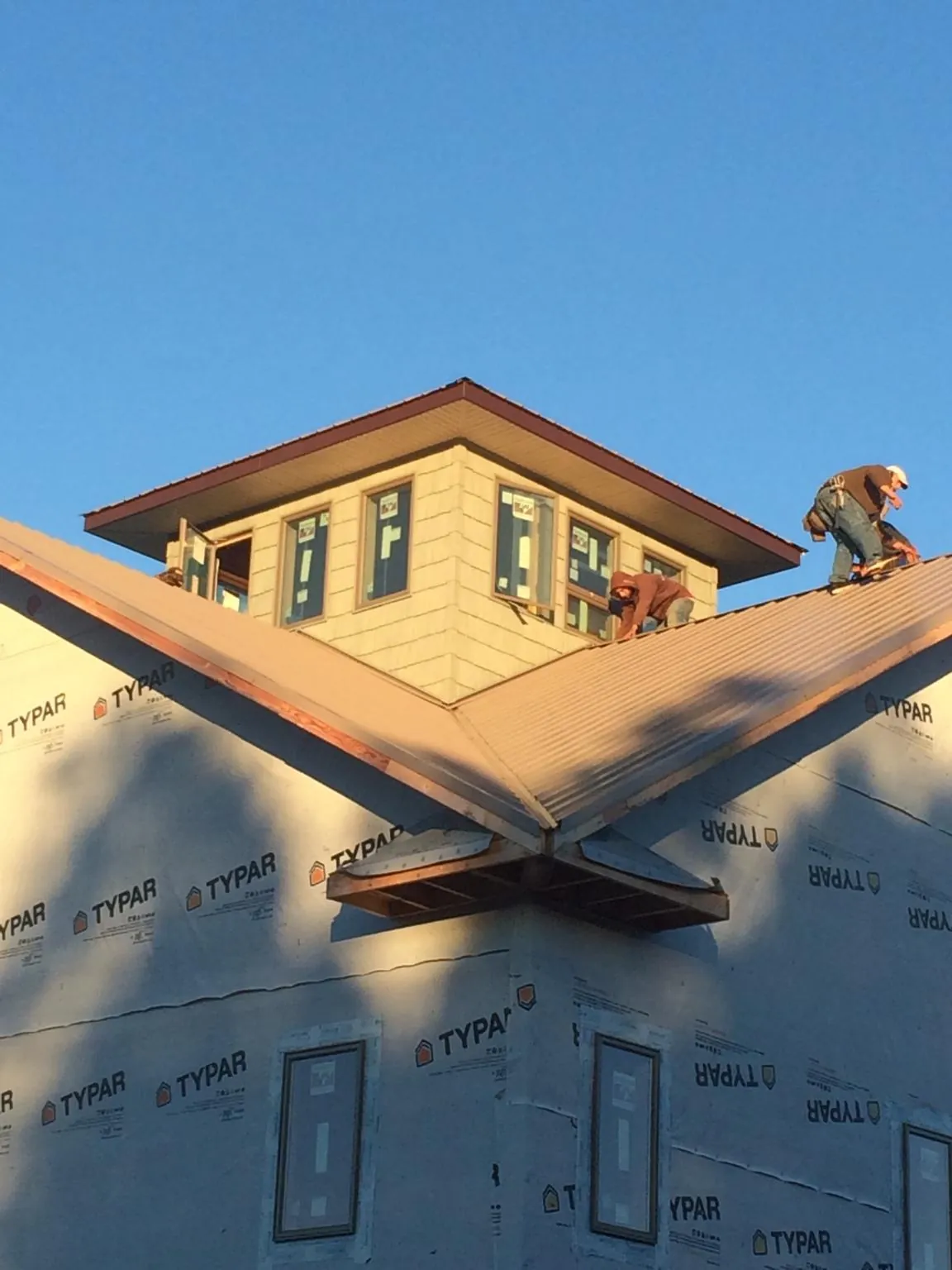 Roofers working around a rooftop cupola on a new metal roof at sunset — Roof Waterproofing in Meadow Grove by Roofing Brothers